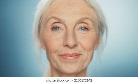 Medium Portrait of Beautiful Senior Woman Looking at Camera and Smiling Wonderfully. Gorgeous Looking Elderly Female with Natural Beauty of Grey Hair, Blue Eyes. Abstract Blue Background
