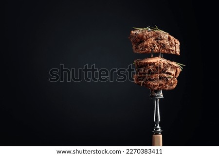 Medium rare beef steak with rosemary on a black background. Copy space.