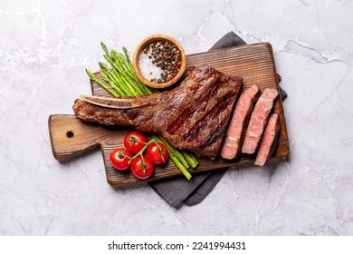 Medium rare grilled Tomahawk beef steak with asparagus. Flat lay