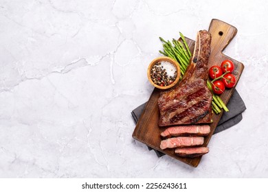 Medium rare grilled Tomahawk beef steak with asparagus. Flat lay with copy space