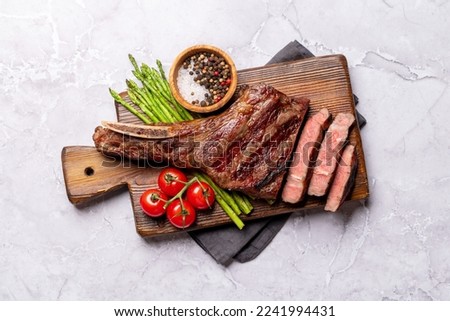 Medium rare grilled Tomahawk beef steak with asparagus. Flat lay