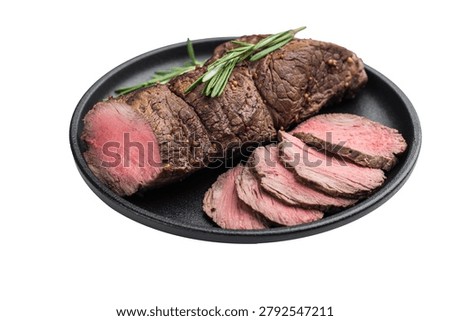 Medium rare roast beef cooked whole and sliced with rosemary. Juicy roasted beef tenderloin served in cast iron pan on white background