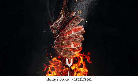 Medium Rare Steak On An Iron Fork On A Dark Background. From Below, Fire And Sparks. Meat And Fire.