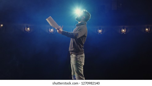 Medium shot of an actor performing a monologue in a theater while holding his script