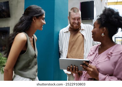 Medium shot of adult smiling man discussing work strategy with African American female manager and fellow colleague at business meeting in office center, positive vibes - Powered by Shutterstock