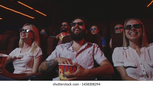 Medium shot of audience laughing while watching comedy movie in a cinema