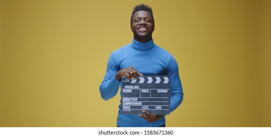 Medium Shot Of Bored Man Using Film Clap Against Yellow Background