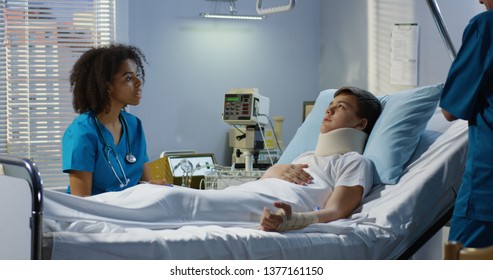 Medium shot of a boy lying in hospital white two nurses caring him