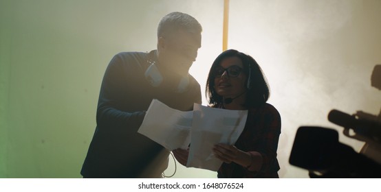 Medium shot of a director holding the script and arguing with a female crew member after a shooting