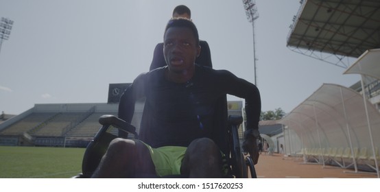 Medium shot of a disabled athlete rolling with wheelchair while being encouraged by his trainer - Powered by Shutterstock