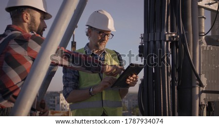 Medium shot of engineers talking while working on 5g antenna