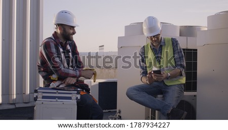 Medium shot of engineers talking while having a break on a cell tower