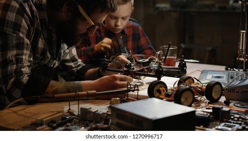 Medium shot of a father and son repairing a drone with wireless control in a garage - Powered by Shutterstock