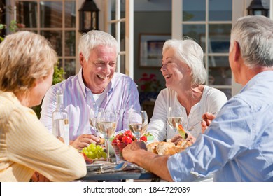 Medium shot of a group of elderly people having lunch and drinking wine at the patio table. - Powered by Shutterstock