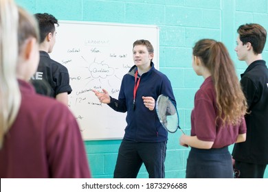 Medium Shot Of A Gym Teacher Teaching High School Students Badminton At The Gymnasium.