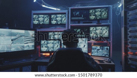 Medium shot of a hacker watching hacked security camera footage