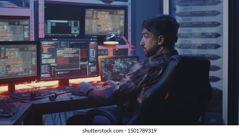 Medium shot of a hacker watching multiple monitors while working
