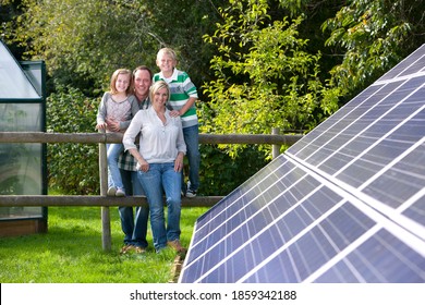 Eine mittelmäßige Aufnahme einer glücklichen Familie, die auf einem Barack in der Nähe eines großen Solarpaneels steht und sich anlehnt.
