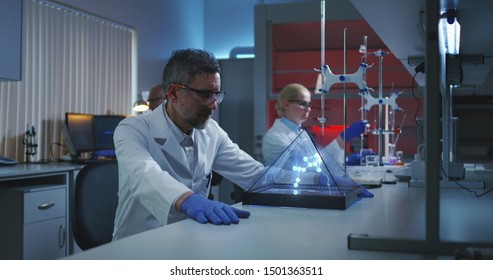 Medium shot of a male scientist examining holographic molecular structure