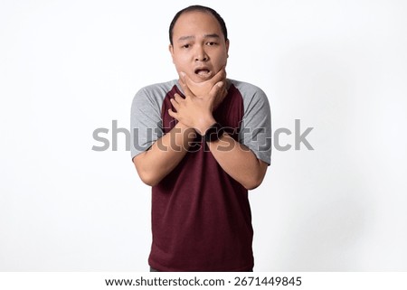 A medium shot of a man with an apprehensive expression, his hands clasped around his throat.