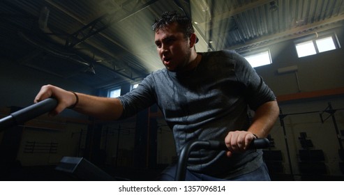 Medium Shot Of An Overweight Young Man Doing An Intense Workout On An Exercise Bike