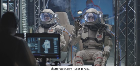 Medium shot of scientists helping a young female and a male astronaut to get ready for a spaceflight - Powered by Shutterstock