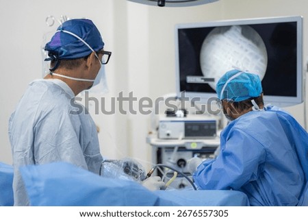 Medium shot of surgeons using endoscopic equipment during minimally invasive surgery in hospital operating room