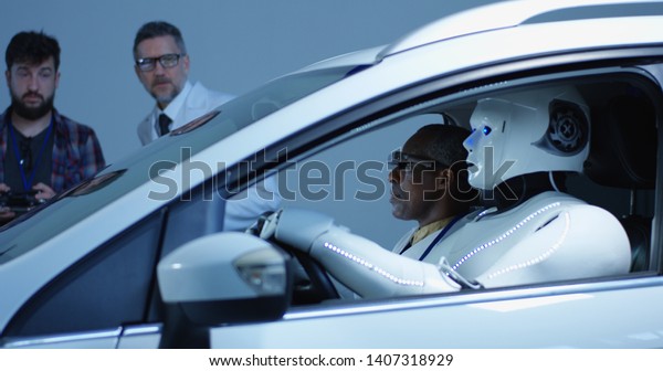 Medium shot of three scientists testing a car\
driving humanoid robot