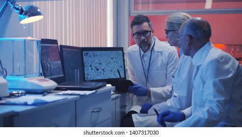 Medium shot of three scientists watching monitor and analyzing