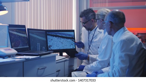 Medium shot of three scientists watching monitor and analyzing