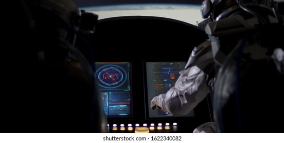 Medium shot of two astronauts using control panel while orbiting around a planet in a spaceship