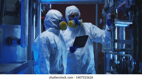 Medium shot of two scientists in hazmat suits conducting maintenance work