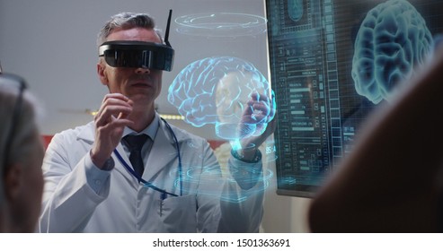 Medium Shot Of A VR Headset Wearing Doctor Explaining To His Colleagues While Moving Holographic 3d Brain Image