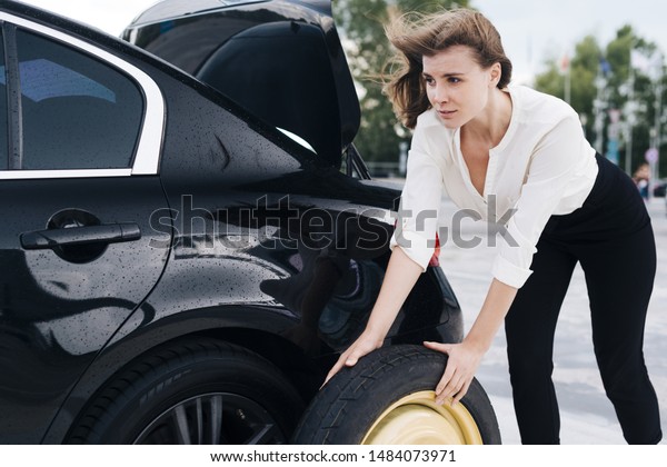 Medium shot of woman changing\
tire