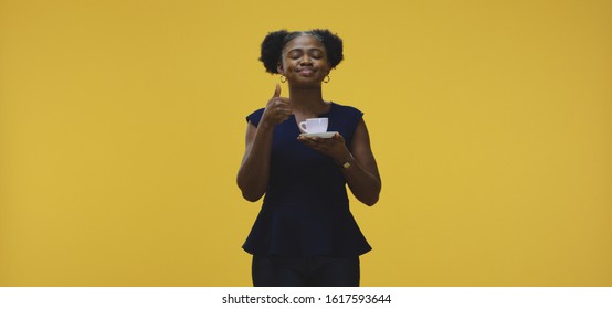 Medium shot of woman tasting coffee against yellow background