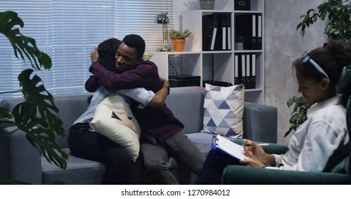 Medium shot of young couple hugging in the office of a psychologist