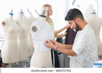 Medium shot of a young fashion design student measuring a garment worn by a mannequin. - Powered by Shutterstock