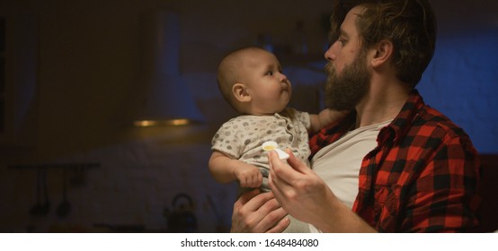 Medium Shot Of A Young Father Feeding Then Handing His Baby Over To Mother At Night