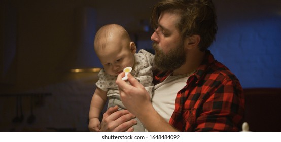 Medium Shot Of A Young Father Feeding His Baby At Night