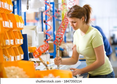 A medium shot of a young female worker in casuals operating machinery on a production line in a factory.