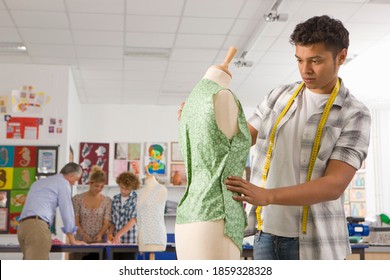 A Medium Shot Of A Young Man Inspecting Dress On A Mannequin In A Home Economics Classroom.