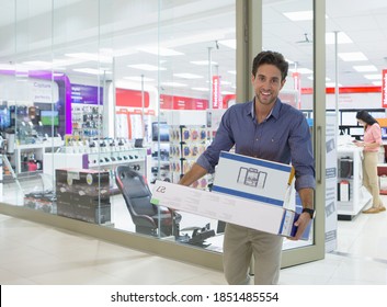 Medium Shot Of A Young Man Leaving An Electronics Store With A Boxes.