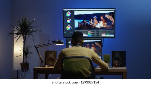 Medium shot of a young man sitting back and editing a video inside a modern video studio