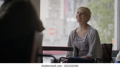 Medium shot of young woman sitting and smiling at a cafe in Downtown Los Angeles, California. Soft focus street in background - Shutterstock ID 2221522181