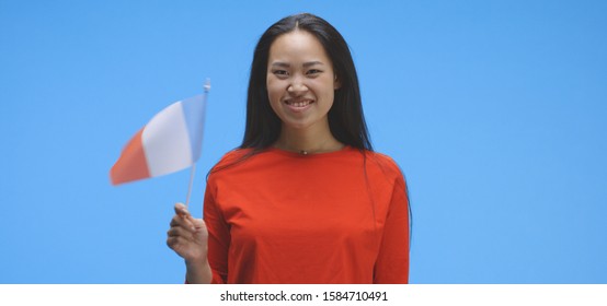 Medium Shot Of Young Woman Waving With French Flag Against Blue Background