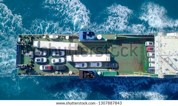 Medium sized Ro-Ro (Roll on/off) ship roaring\
across The Mediterranean Sea with cars and trucks seen on the upper\
deck - Aerial image.