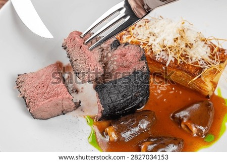 Medium-rare beef steak slices presented on a white plate with sauce, garnished with crispy onions and mushrooms for an elegant dining experience