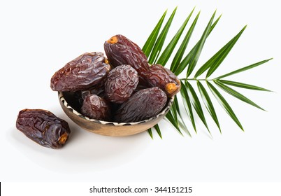 Medjool dates in a bowl and green leaf isolated on white background