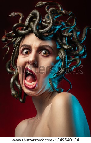 medusa gorgon with bare shoulders looking at camera on red background, screaming