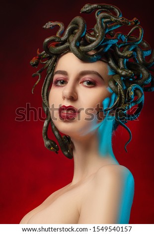 medusa gorgon with bare shoulders looking at camera on red background
